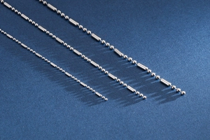 Vue macro de trois chaînes à billes en acier inoxydable sur fond bleu foncé mat