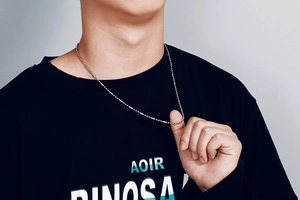 Gros plan d'un collier en acier inoxydable argenté sur un mannequin homme en t-shirt noir