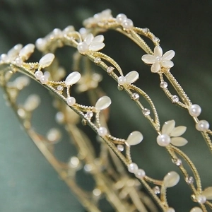 Elegant gold vine leaf headband with cat eye stone flowers and pearls on green background