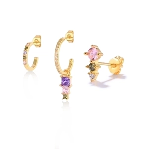 Detailed macro view of three gold earrings featuring colorful zircon stones on white background