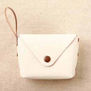 Detail of cream envelope coin purse with vintage bronze snap button and wrist strap