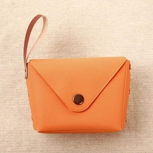 Detail of vibrant orange leather coin purse with bronze snap button on burlap background