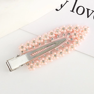 Detailed macro view of a pink flower hair clip featuring faux pearls and rhinestones