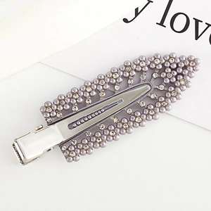 Detail of silver hair clip with purple pearls and rhinestones on a decorative card