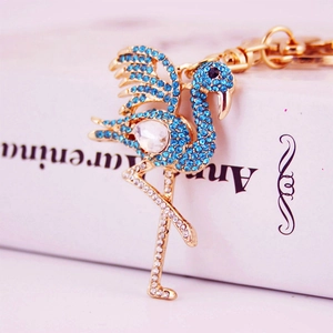 Golden flamingo keychain with sparkling blue and clear rhinestones on a vintage book