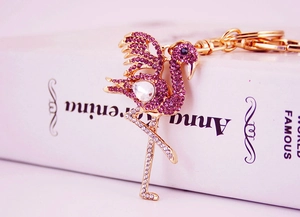 Close-up of pink crystal flamingo keychain with gold finish on an open book background