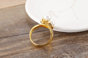 Macro shot of gold titanium ring featuring white pearls and leaf-shaped crystal detail