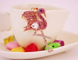 Detail shot of a pink crystal flamingo keychain resting on a white ceramic mug