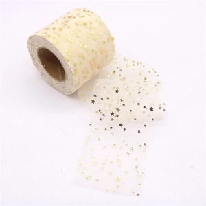 Macro view of ivory tulle ribbon roll with shiny gold foil star patterns for DIY crafts