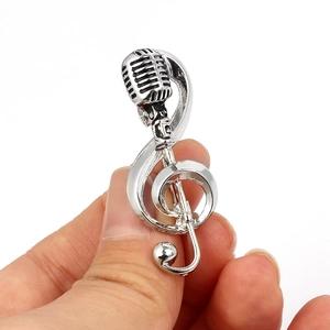 Vintage silver microphone and musical note brooch with polished metallic finish