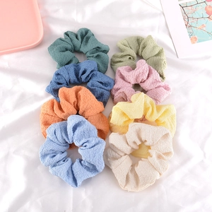 Set of colorful seersucker scrunchies in pastel tones on a white silk background