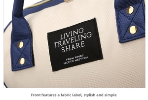 Detail of oxford fabric diaper bag with navy blue handles and white woven label logo