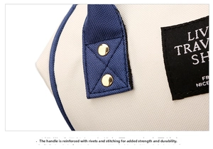 Close-up of reinforced handle with gold rivets and X-shaped stitching on oxford baby bag