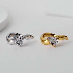 Macro detail of teardrop-shaped zircon earrings in gold and silver finishes
