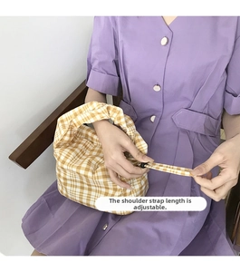 Détail de la boucle réglable et de la bandoulière à carreaux jaunes de ce sac baguette
