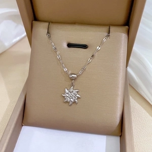 Macro detail of a silver geometric star pendant necklace inside a beige jewelry gift box