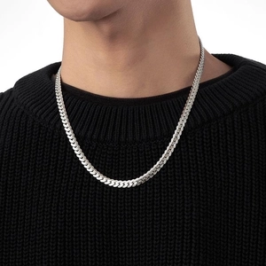 Detail of silver titanium steel flat curb chain necklace on black sweater worn by a model