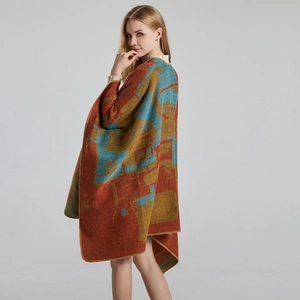 Detail of soft jacquard knit poncho with warm orange geometric patterns and stitched edges