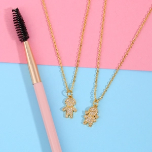 Detail of couple necklaces with gold boys and girls pendants encrusted with white zircons
