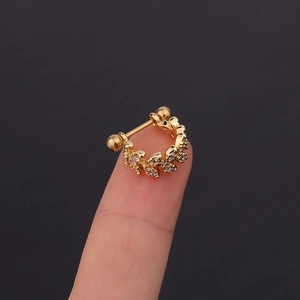 U-shaped gold stainless steel ear cuff with leaf zircon studs shown on a fingertip