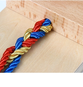 Close-up of colorful red, blue, and yellow braided rope on natural wood background