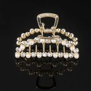 Detail of gold metal hair claw clip with inlaid pearls and sparkling rhinestones