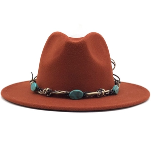 Detail of rust-red wool fedora featuring a woven band with turquoise stone beads