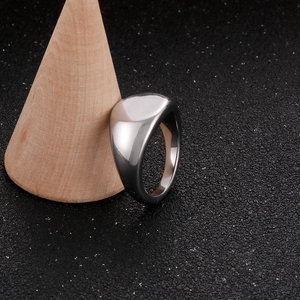 Close-up of polished silver signet ring on a wooden stand with a black textured backdrop