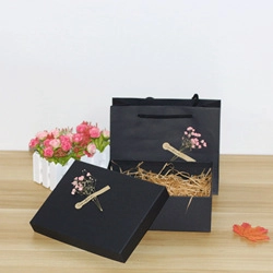 Detail of elegant black gift box and matching paper bag with dried flower decor