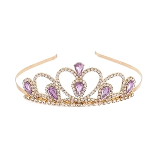 Golden princess tiara with purple teardrop crystals and rhinestones on a white backdrop