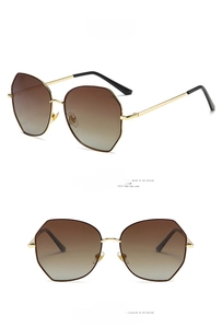 Detail view of large geometric sunglasses with tea gold metal frames and gradient brown lenses