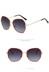 Detail view of round sunglasses with red gold polygonal frames and gradient grey lenses