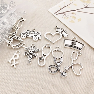 Macro shot of silver medical charms including nurse hats and stethoscopes for DIY jewelry