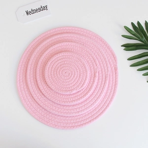 Set of four stacked pink round woven cotton coasters showing braided texture detail
