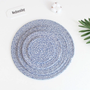 Detail of four round blue and white woven cotton heat-resistant coasters on white surface