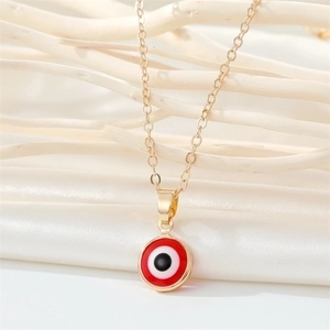 Gold stainless steel evil eye necklace with red enamel pendant on textured background