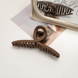 Macro detail of large mocha brown matte hair claw clip with cross spiral design