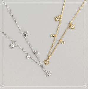 Detailed view of silver and gold geometric star necklaces with zircon stone accents