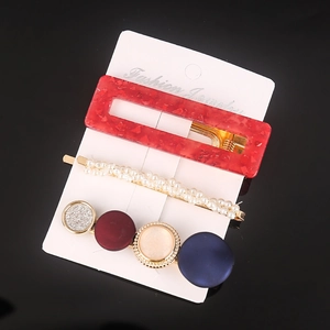 Close-up of hair clip set featuring red marble acrylic, pearls and geometric shapes