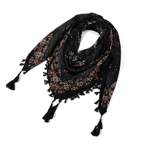 Close-up of bohemian floral paisley patterns and tassel edges on a soft black scarf
