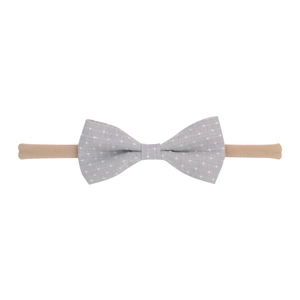Close-up of a grey bow headband with white polka dots on a nude elastic nylon band