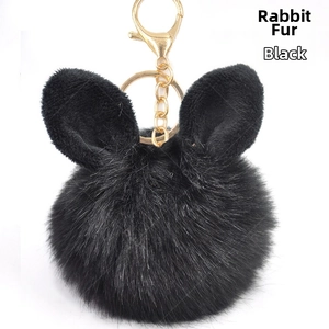 Detailed view of black fluffy faux fur pompom keychain with cute rabbit ears and gold hardware