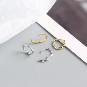Detailed view of twisted S925 sterling silver huggie hoop earrings in gold and silver