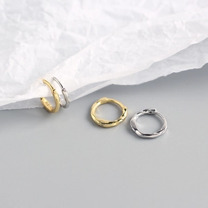 Macro shot of minimalist twisted rope hoop earrings in polished gold and silver finish