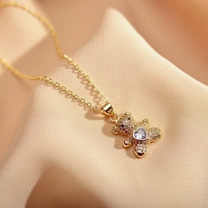 Detailed close-up of a gold teddy bear pendant necklace with heart-shaped gemstone