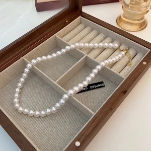 Close-up of pearl necklace with 14K gold plated pendant in a wooden jewelry box