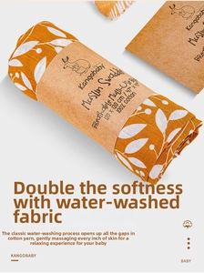 Detail of 100% cotton muslin swaddle blanket with white leaf patterns and paper packaging