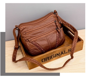 Detail of brown vintage crossbody bag featuring woven texture and zipper pockets
