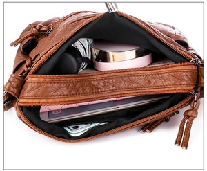 Top-down view of a spacious brown soft leather bag interior with multiple compartments
