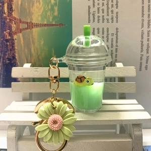 Detail of creative acrylic keychain with floating turtle in milk tea cup and green daisy charm